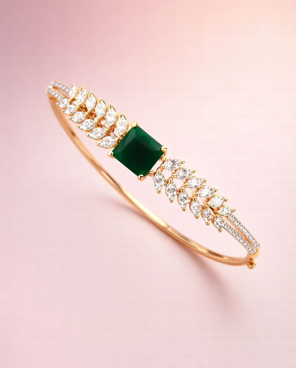 Gold bracelet with a green gemstone on a pink background
