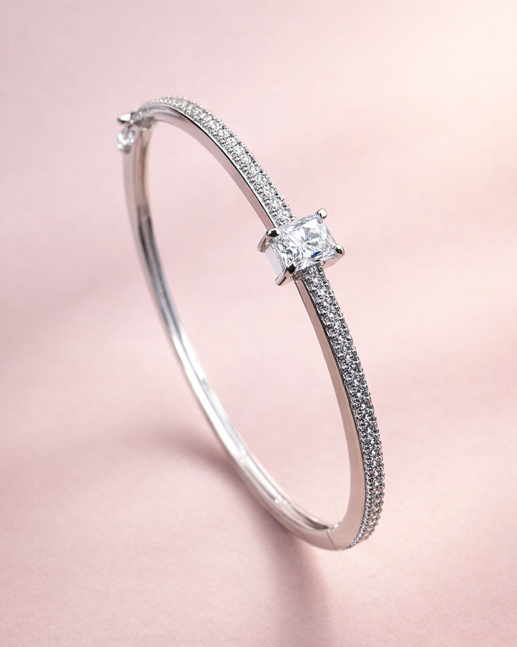 Silver bracelet with a central diamond on a pink background
