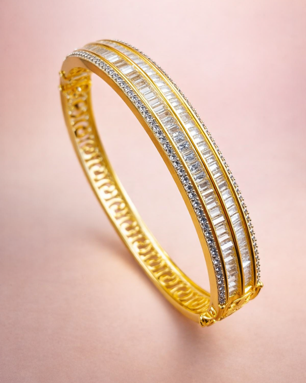 Gold bracelet with embedded stones on a pink background
