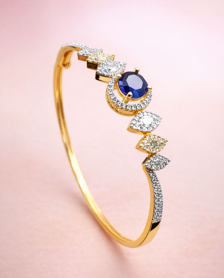 Gold bracelet with a blue gemstone and diamonds on a pink background
