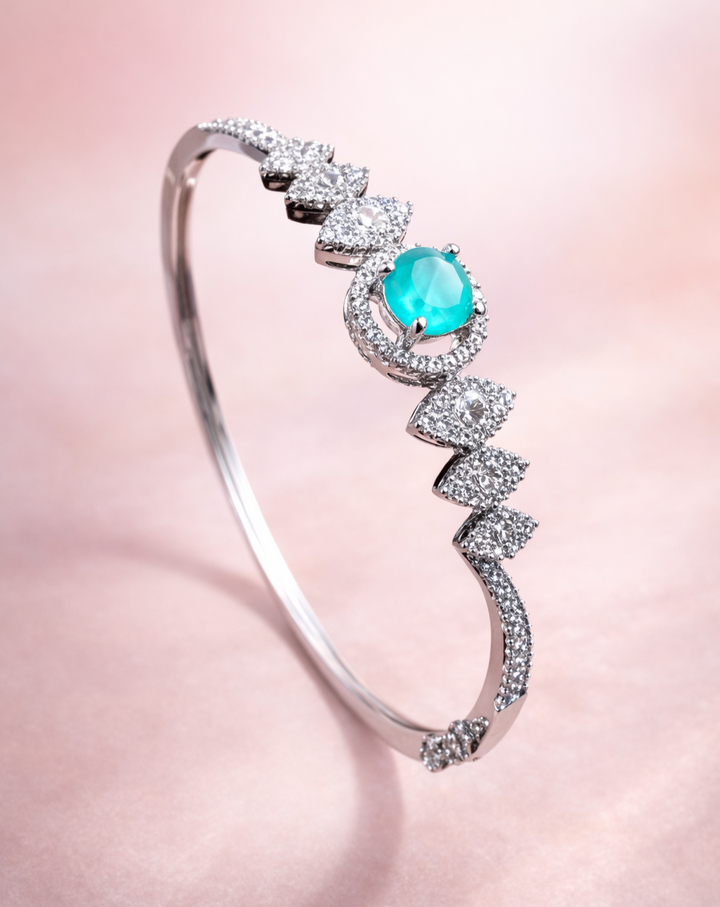 Silver bracelet with a turquoise gemstone on a pink background