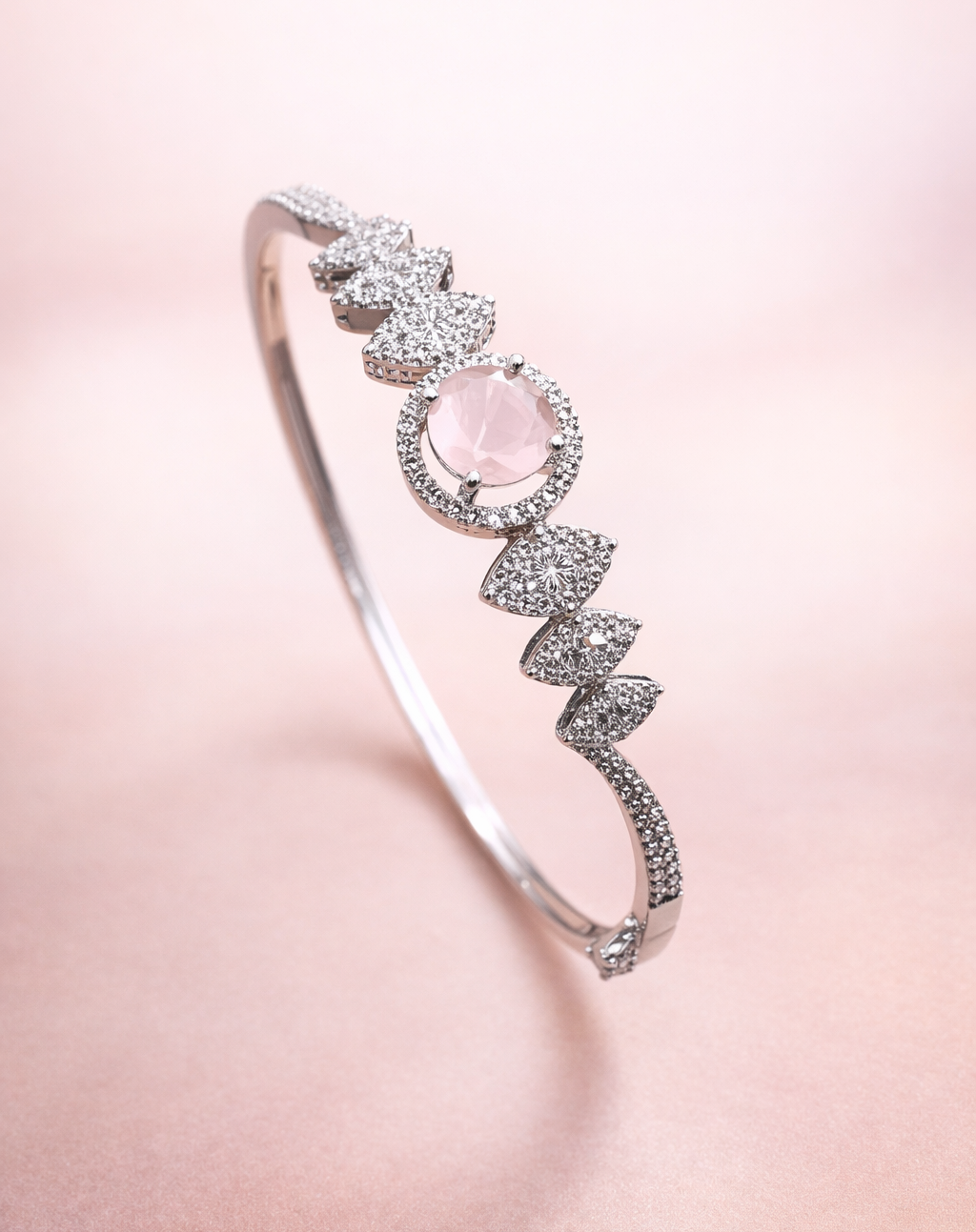 Silver bracelet with a pink gemstone on a soft pink background