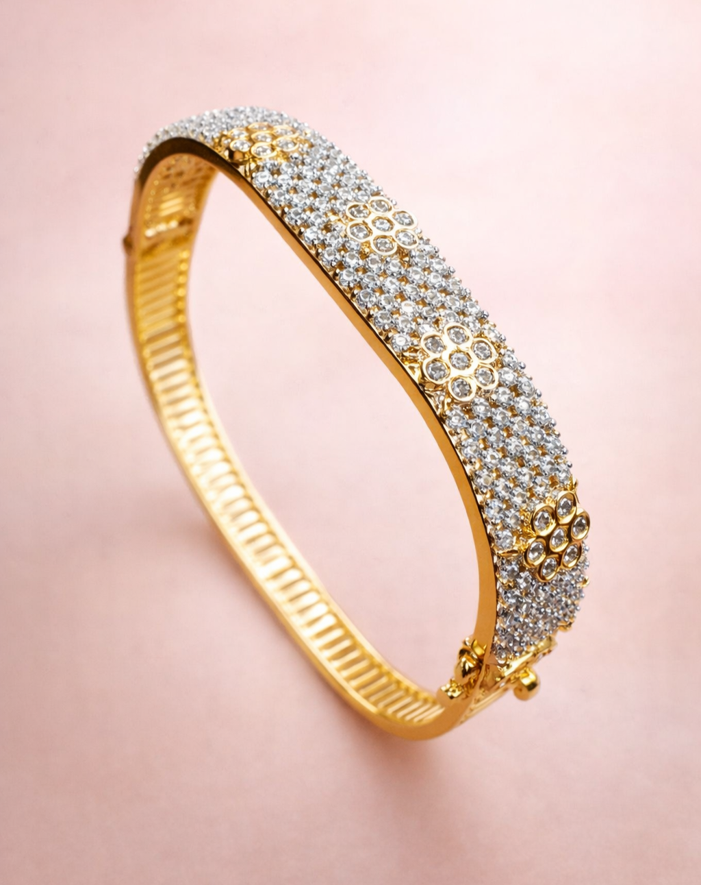 Gold bracelet with diamond accents on a pink background