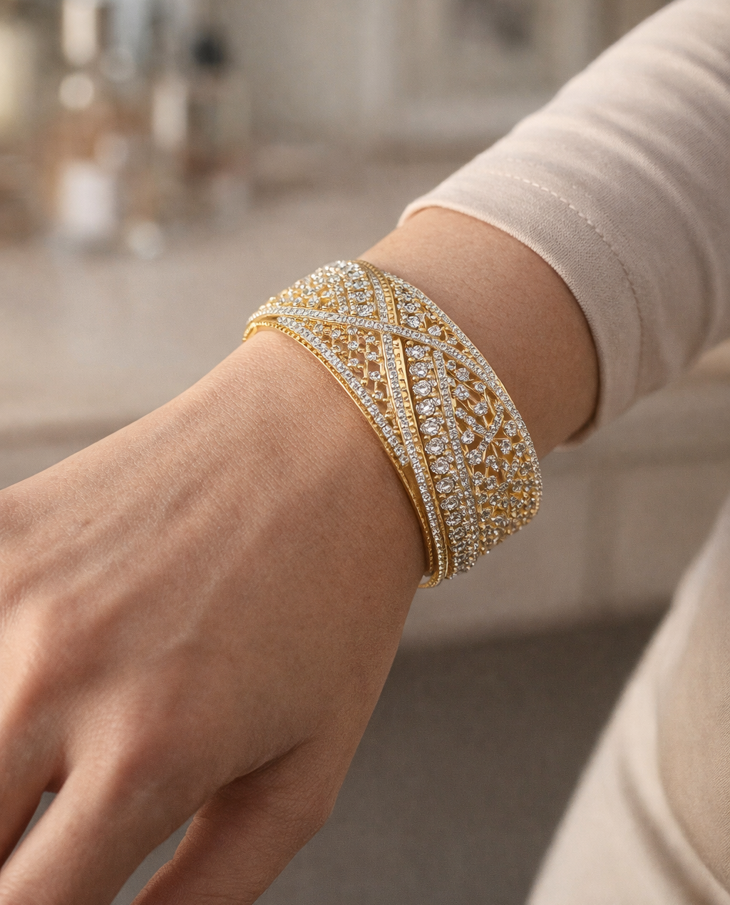 Gold bracelet with intricate design on a wrist against a neutral background