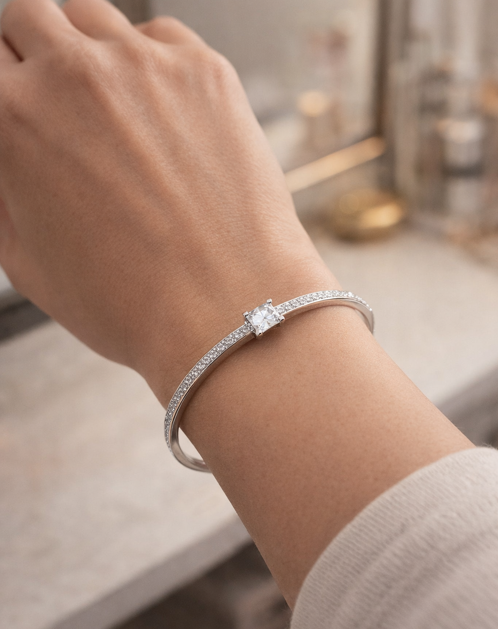Silver bracelet with a diamond on a wrist against a blurred indoor background