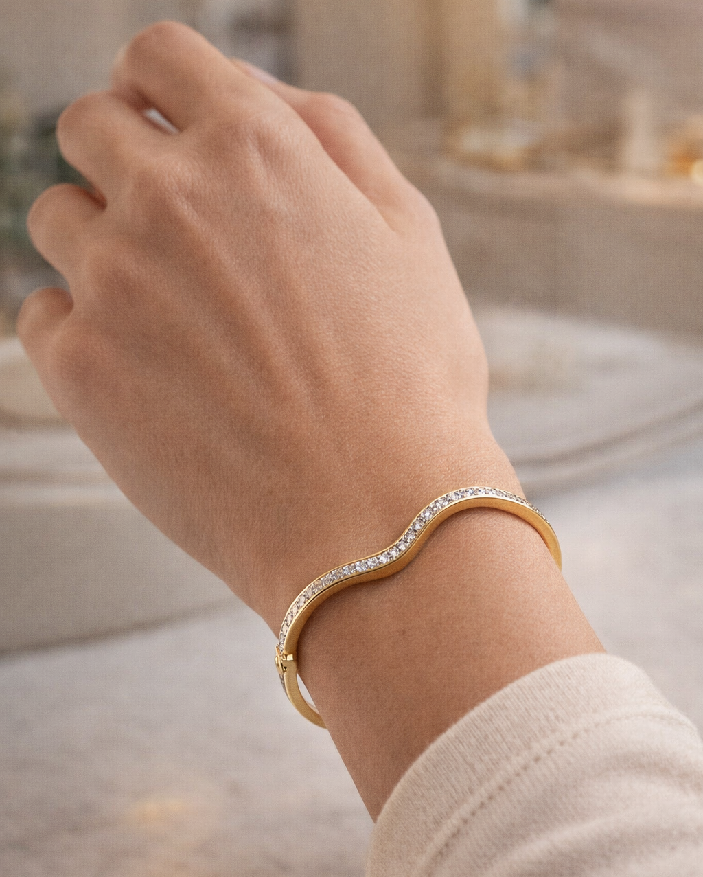 Gold bracelet with clear stones on a wrist against a blurred background