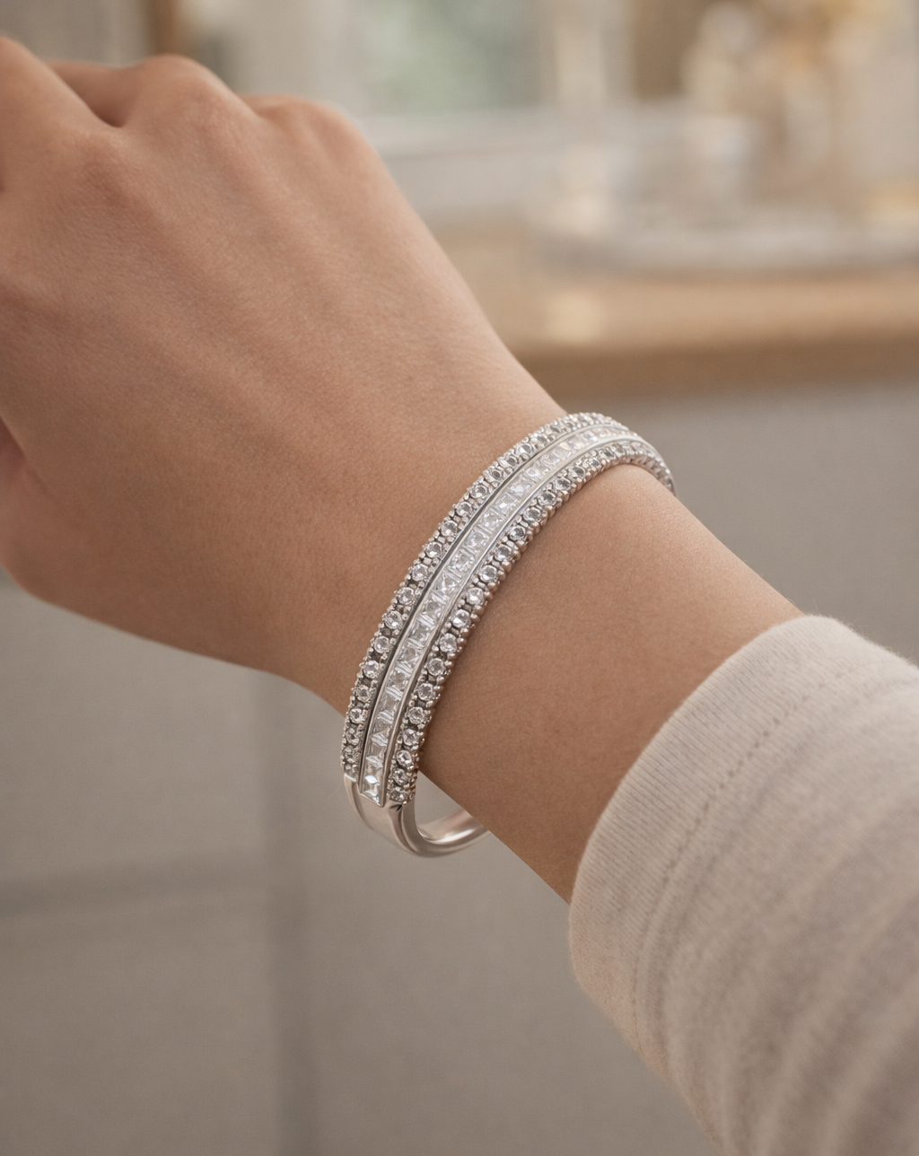 Close-up of a hand wearing two silver bracelets with a blurred background