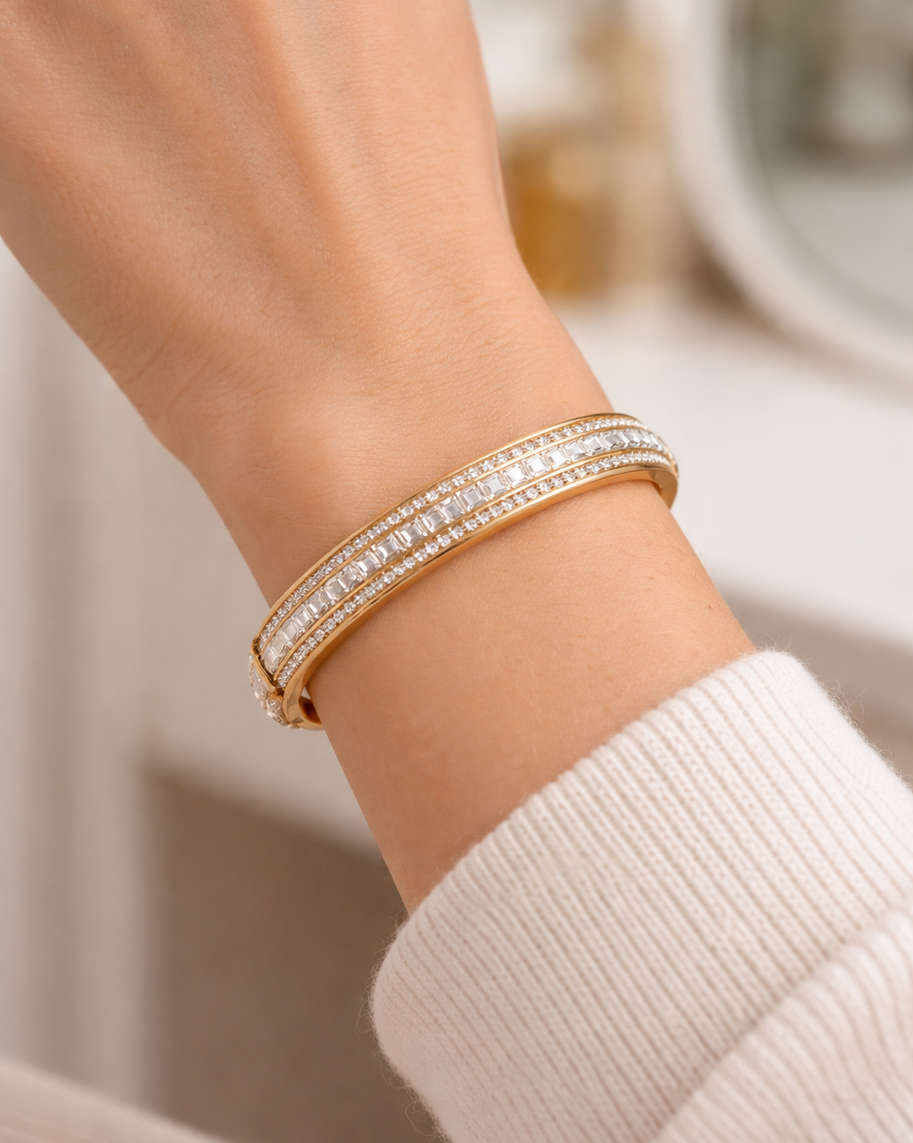 Gold bracelet with clear stones on a wrist against a neutral background