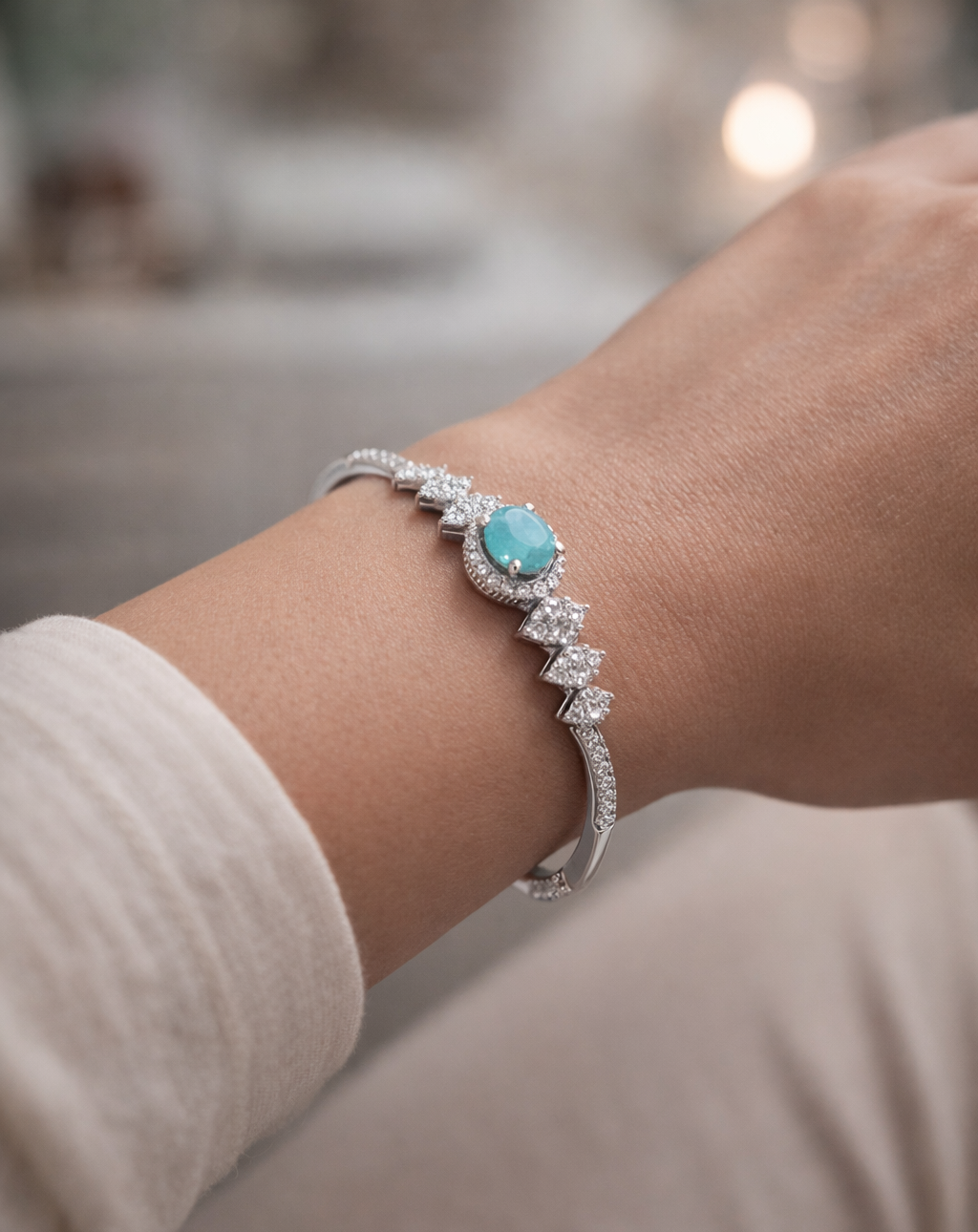 Silver bracelet with a turquoise stone on a wrist against a blurred background