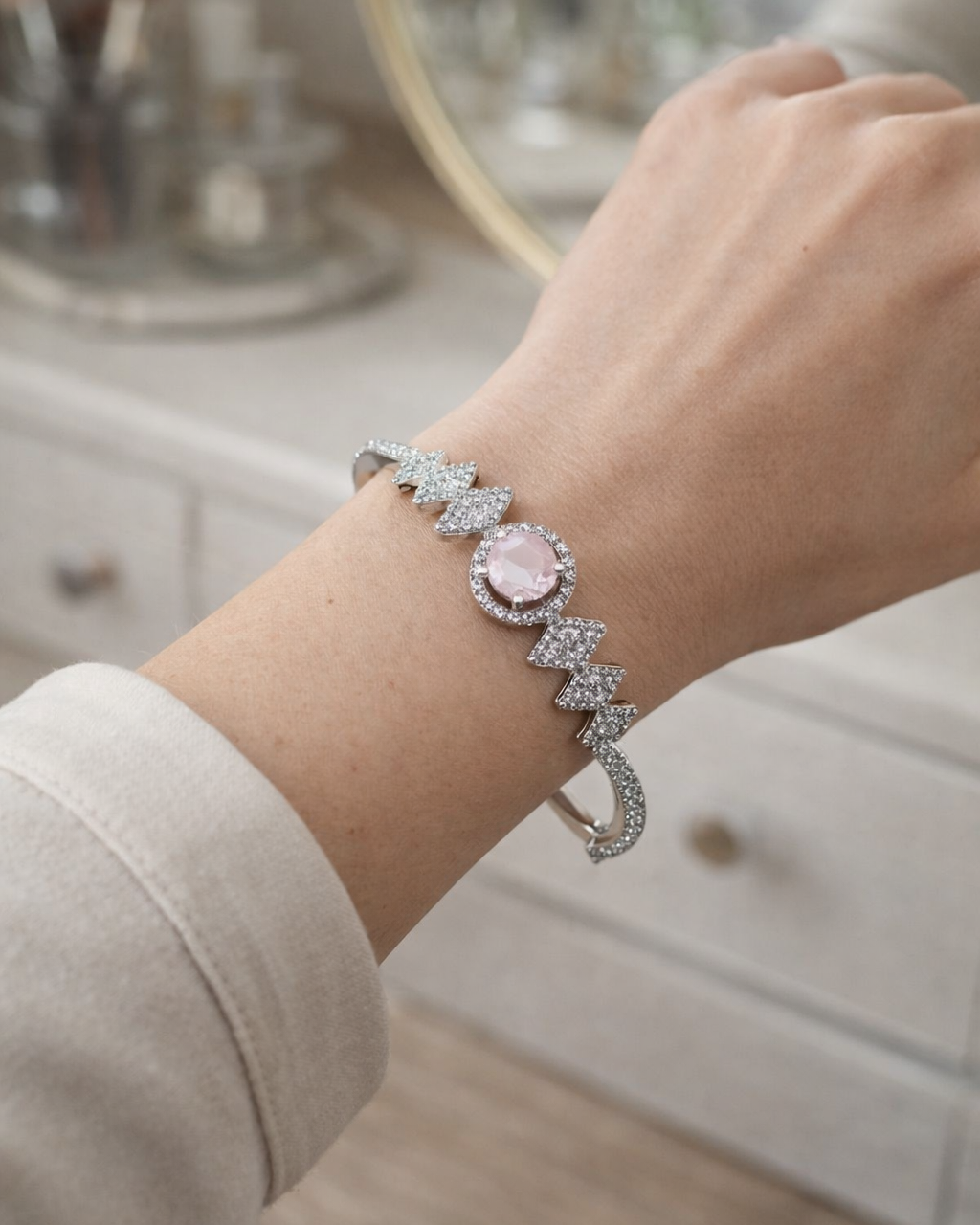 Silver bracelet with a pink gemstone on a wrist, blurred background