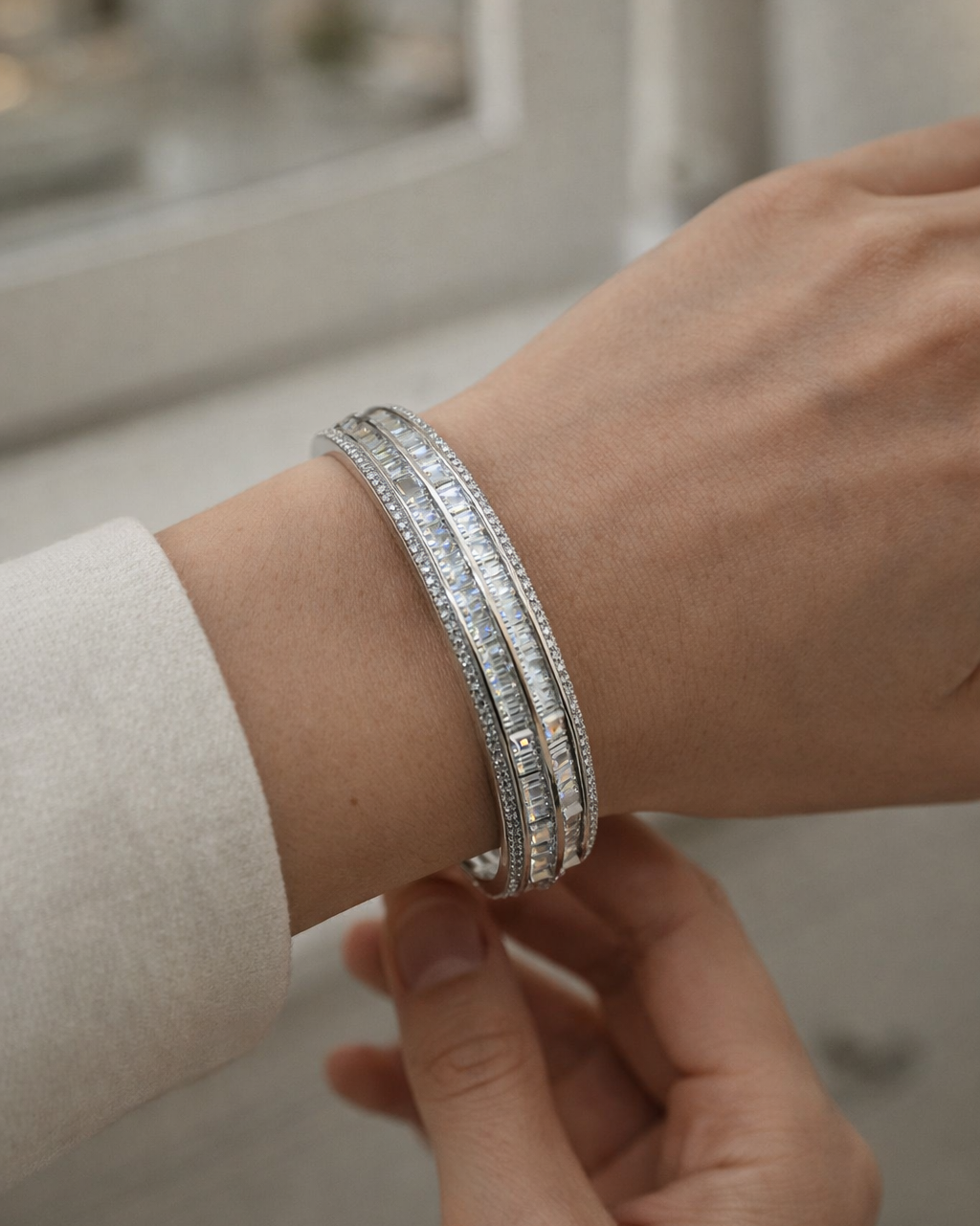 Close-up of a wrist wearing multiple diamond bracelets with a neutral background.