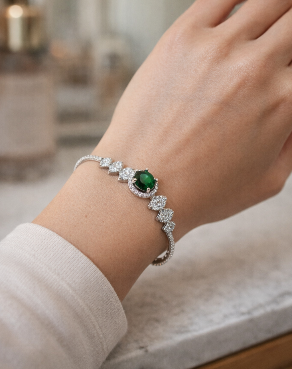 Bracelet with a green gemstone on a wrist, blurred background