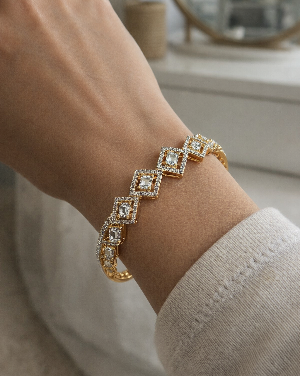 Gold bracelet with diamond-like stones on a wrist, blurred background