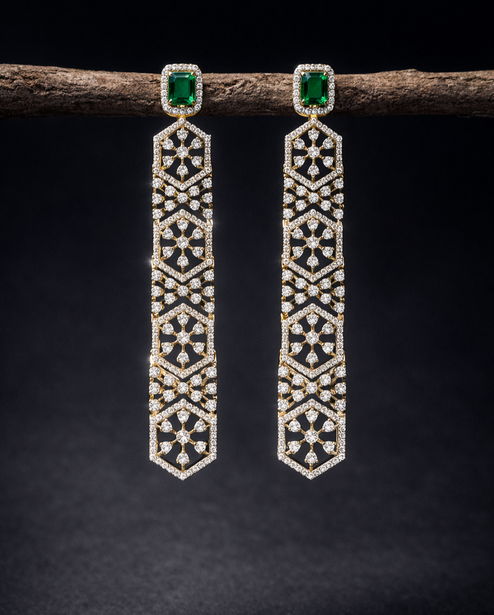 Pair of diamond earrings with green gemstones on a dark background