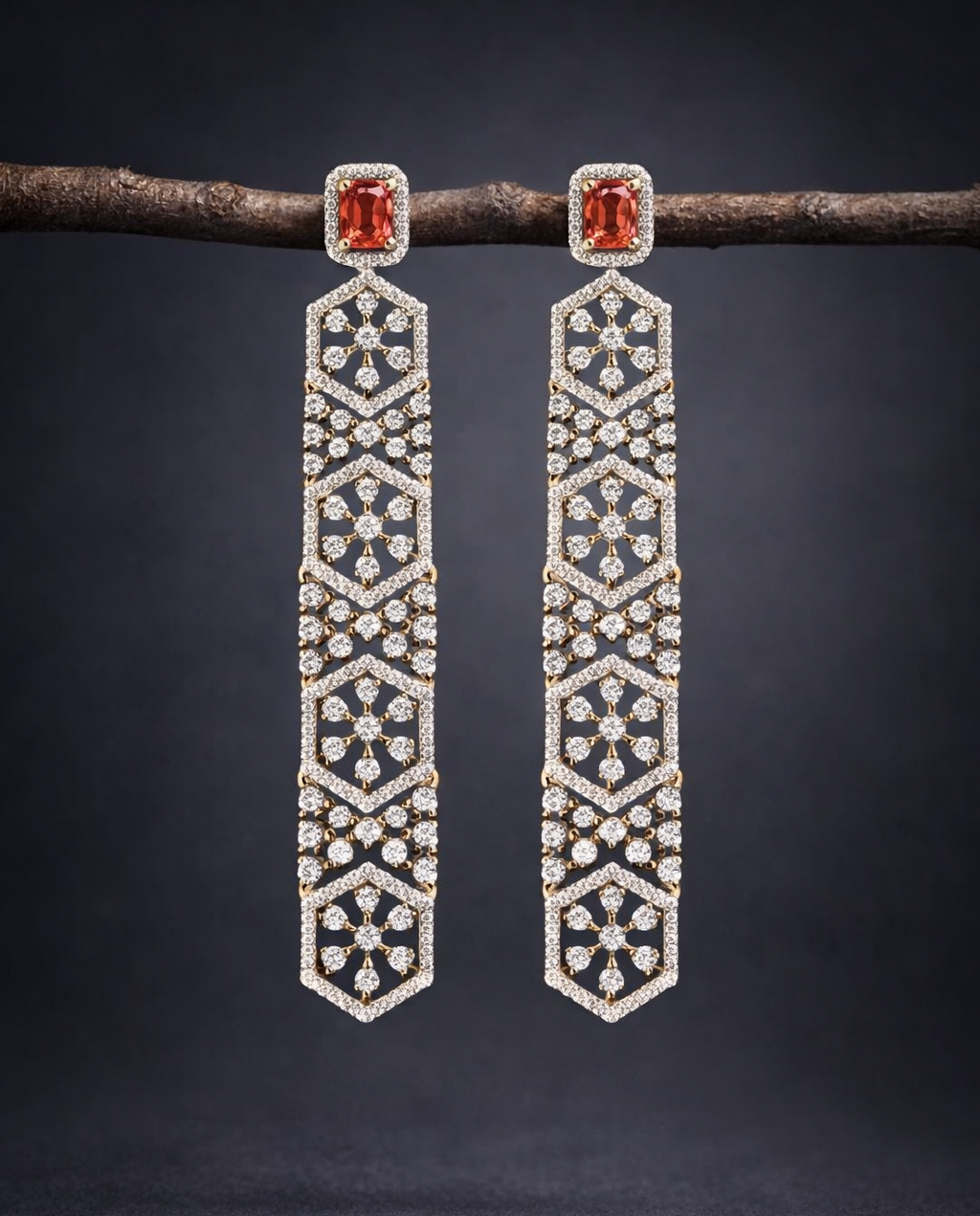 Pair of long, ornate earrings with gemstones on a dark background