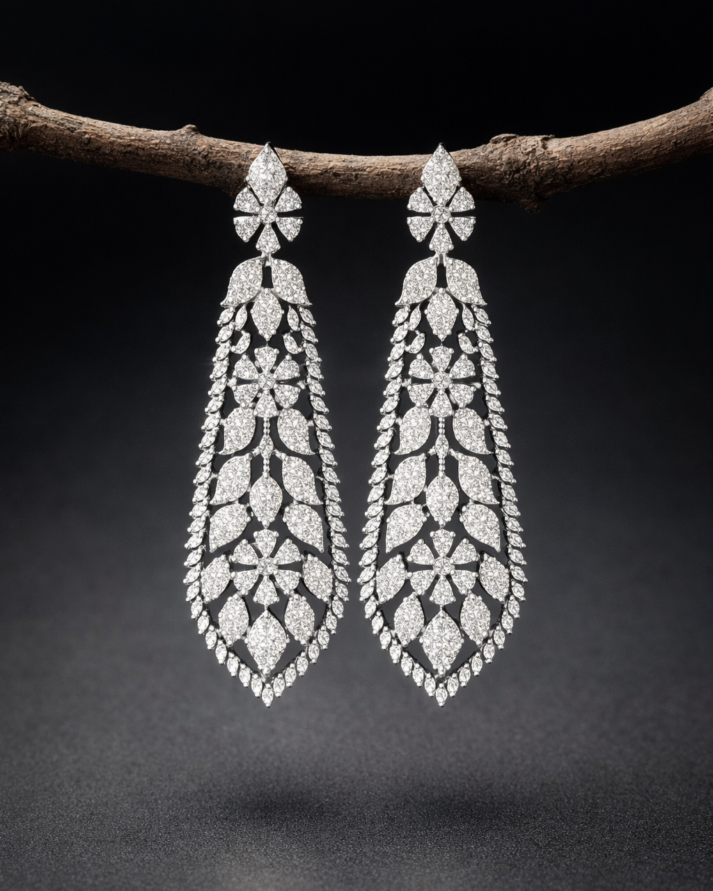 Pair of diamond earrings hanging on a branch against a dark background