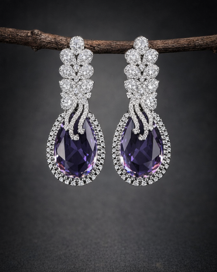 Pair of purple teardrop earrings with silver accents on a dark background