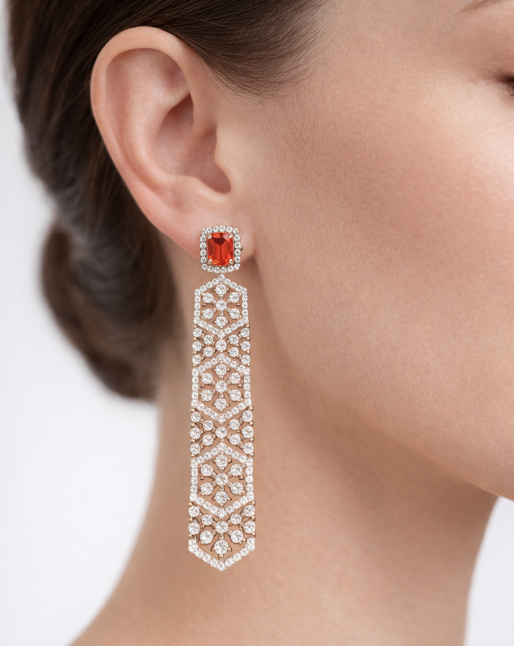 Earring with a red gemstone and diamond lattice design on a neutral background