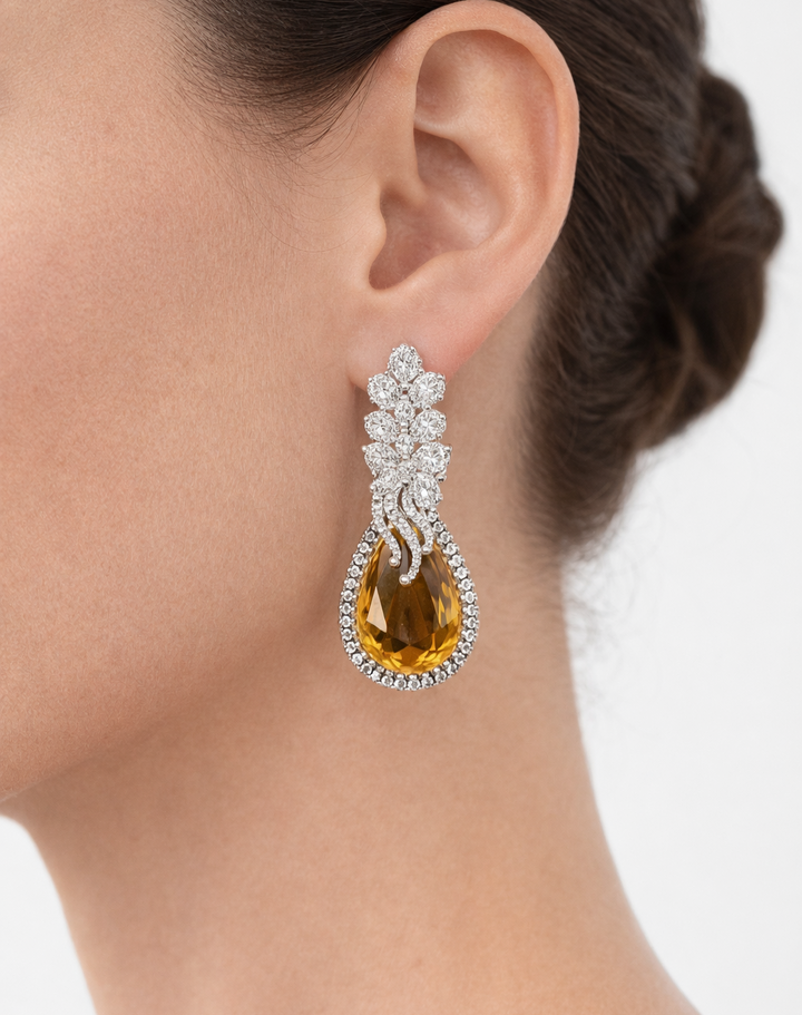Earring with a yellow gemstone and silver floral design worn by a person.