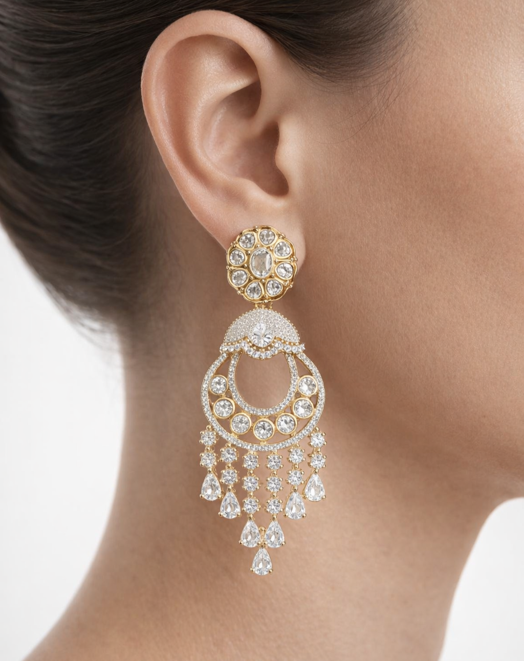 Gold and diamond earring worn by a person on a white background
