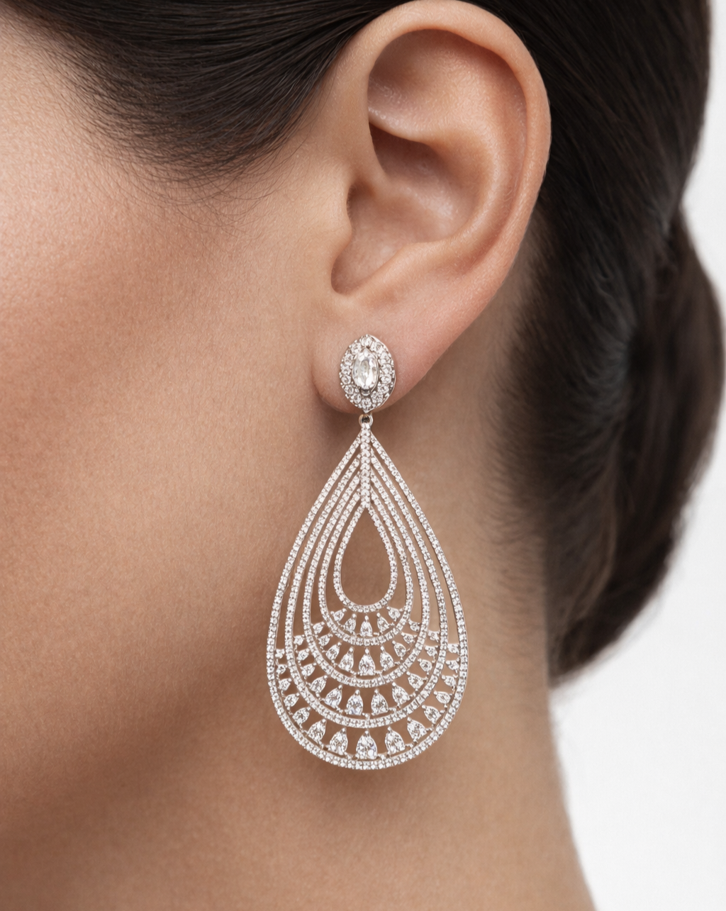 Teardrop-shaped diamond earring worn by a model on a neutral background