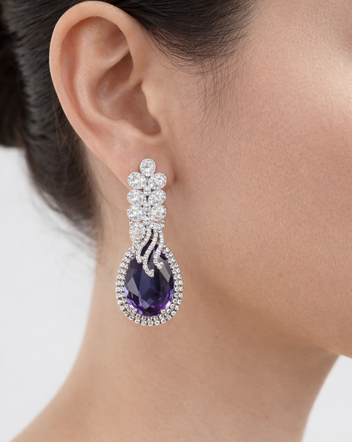 Earring with purple gemstone and diamond-like stones worn by a person.
