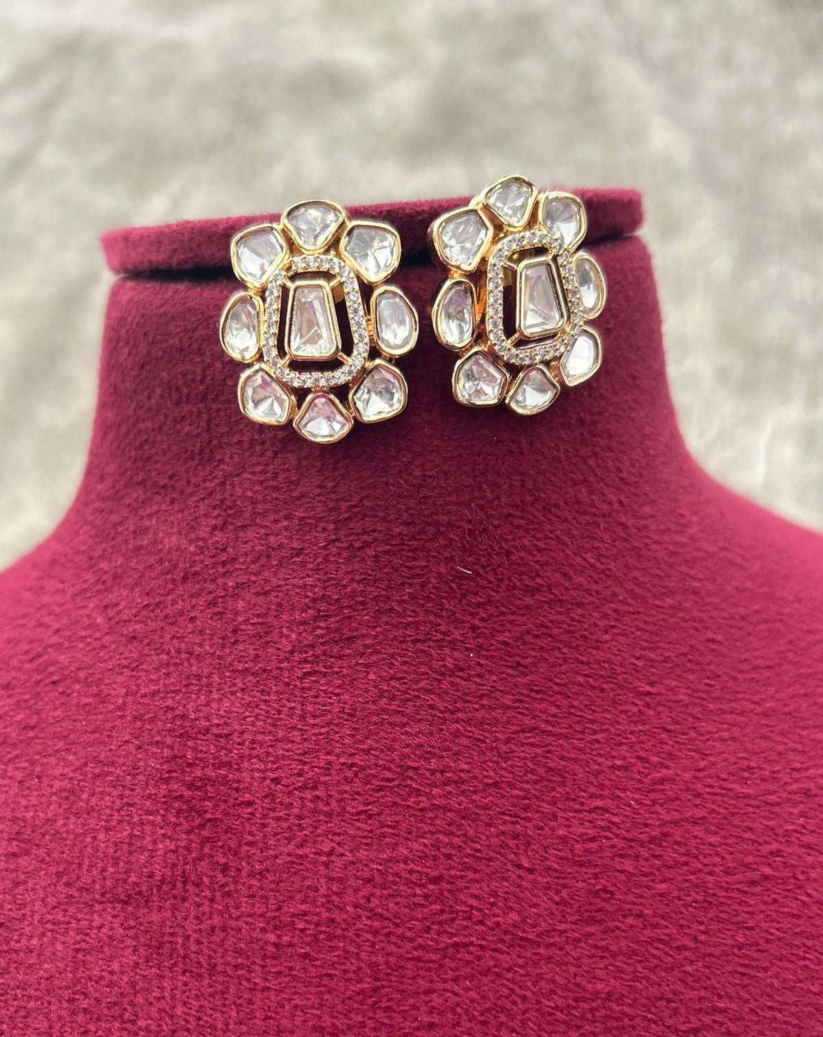 Decorative earrings on a mannequin with a textured background