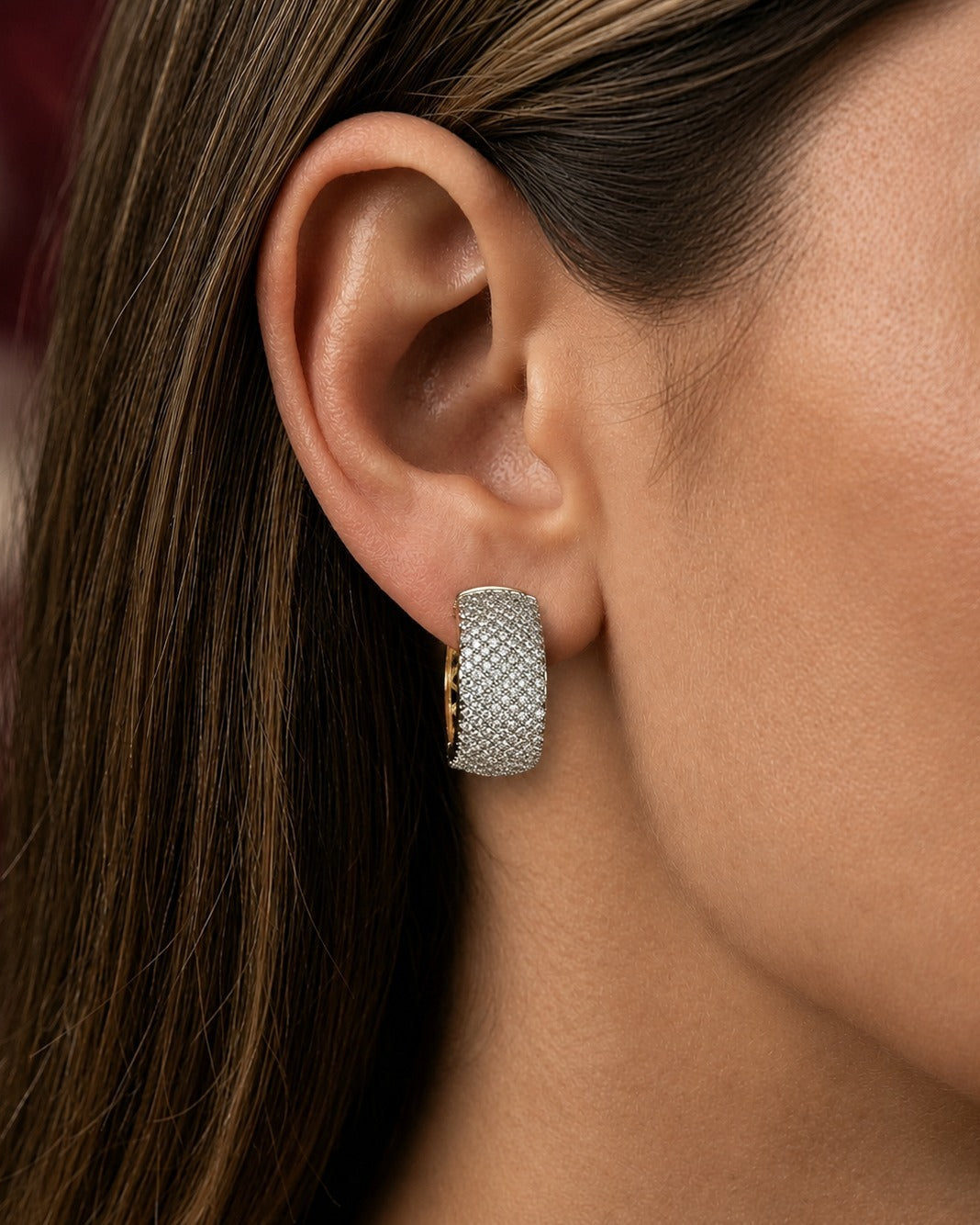 A close-up of a woman's ear wearing a textured silver hoop earring with a pavé diamond setting.
