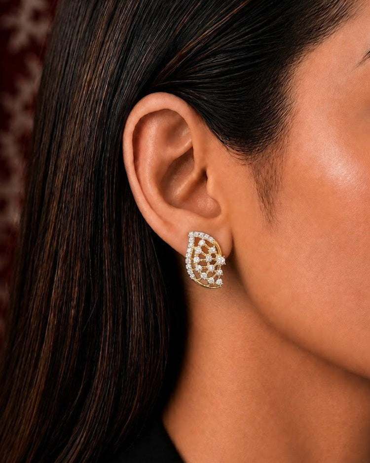 A close-up side profile of a woman wearing a teardrop-shaped gold and white stone stud earring.