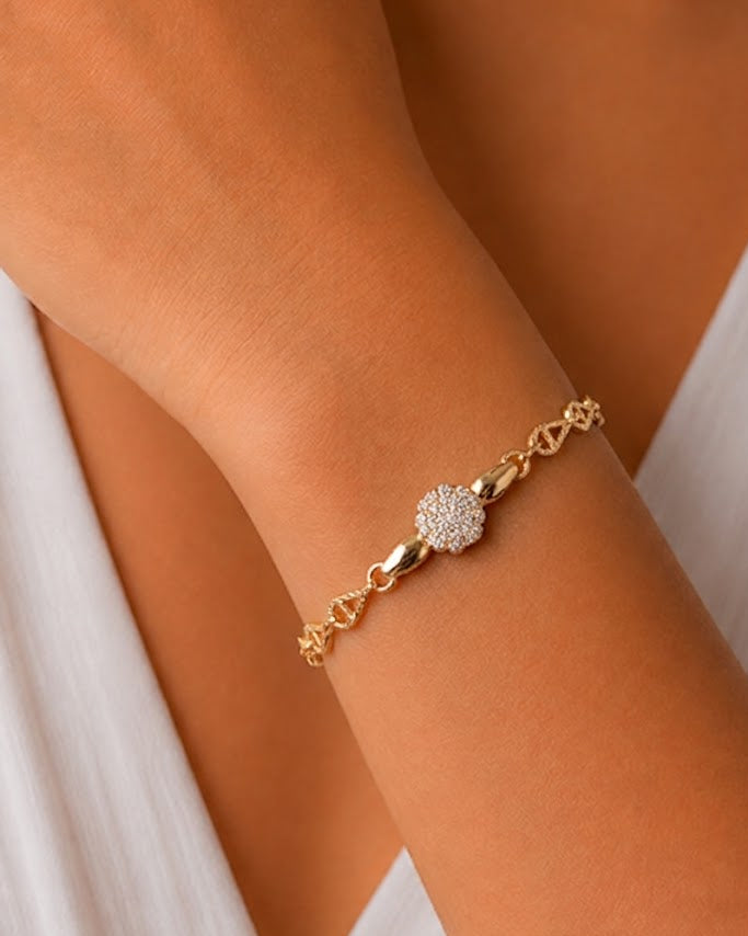 A delicate gold chain bracelet with a central pavé diamond flower clasp, shown worn on a model's wrist.