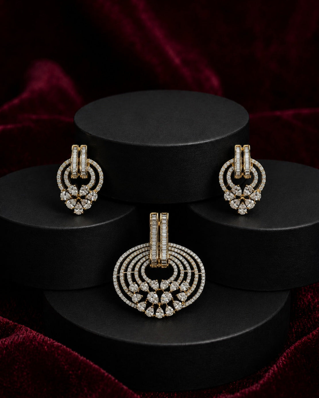 A gold and diamond jewelry set displayed on black cylindrical pedestals against a deep red velvet background. The set includes a large circular pendant and two matching earrings.