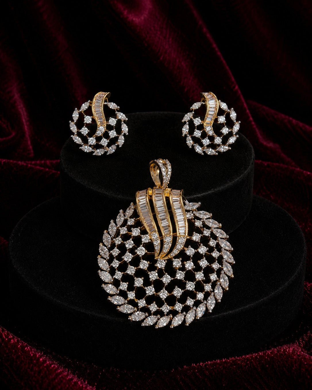 A gold and diamond jewelry set featuring a large round pendant, matching earrings, and a small necklace, displayed on black velvet stands against a dark red velvet background.