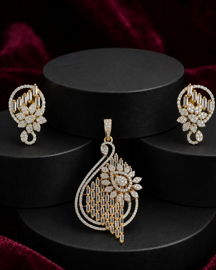 A gold and diamond jewelry set featuring a large teardrop pendant, matching earrings, and a small nose stud, displayed on black cylindrical pedestals against a dark red velvet background.