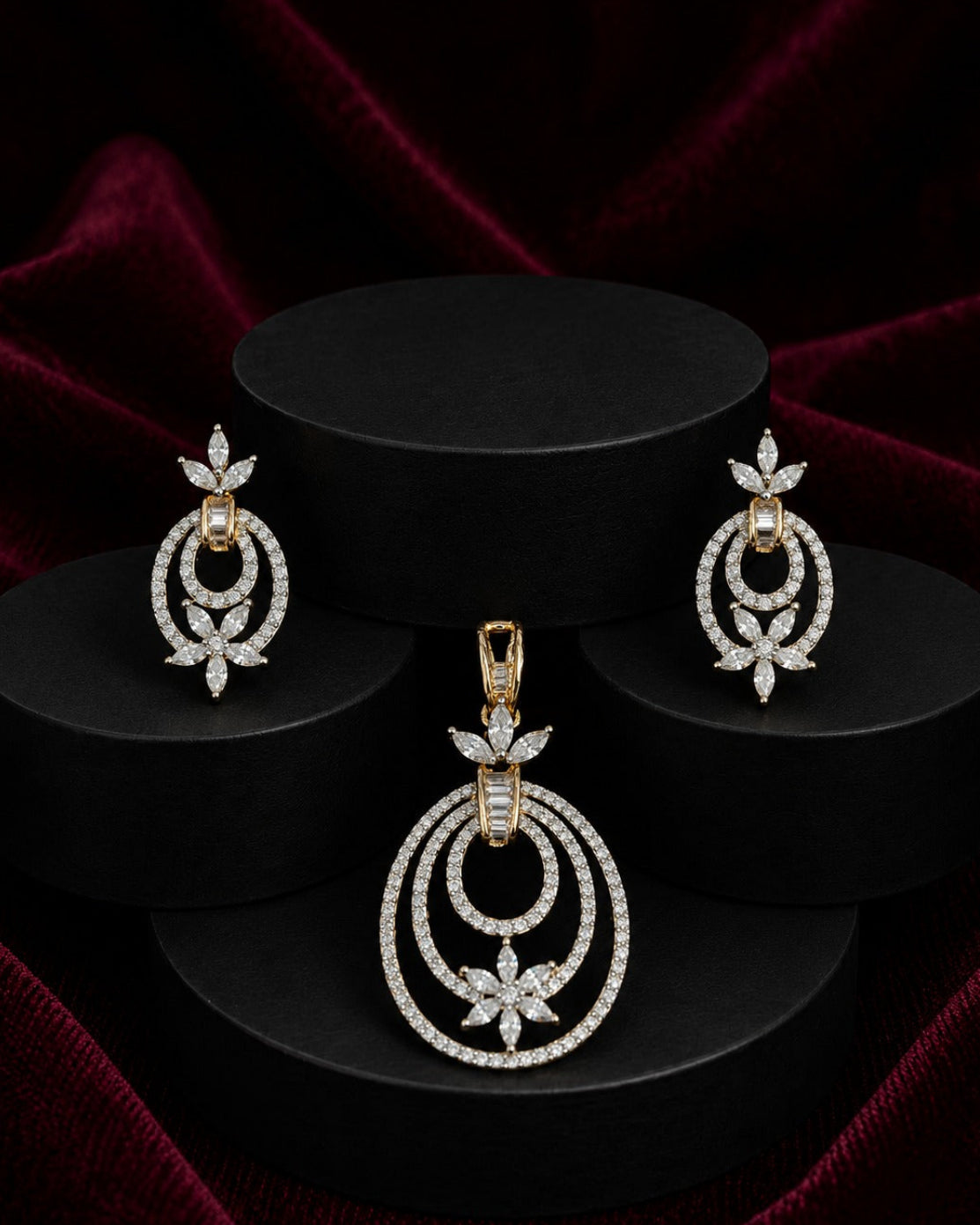 A gold and diamond jewelry set featuring a pendant, matching earrings,  displayed on black cylindrical pedestals against a dark red velvet background.