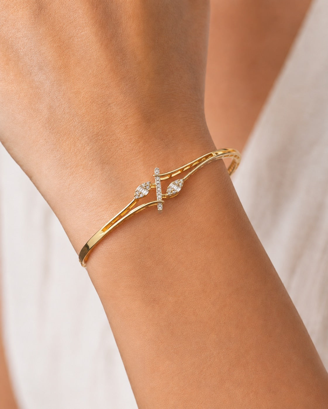 A gold bangle bracelet with a central pavé bar and diamond-set heart motifs, shown worn on a person's wrist.