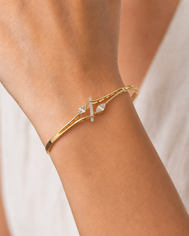 A gold bangle bracelet with a central pavé bar and diamond-set heart motifs, shown worn on a person's wrist.