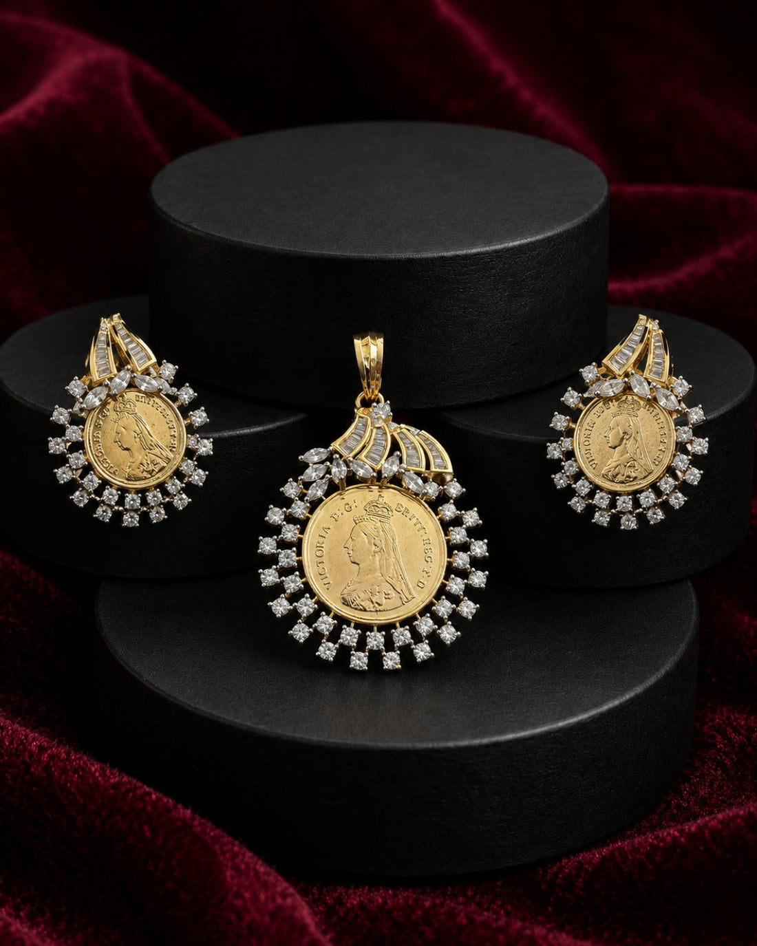 A gold coin pendant necklace with diamond accents, displayed alongside matching earrings on black cylindrical pedestals against a dark red velvet background.