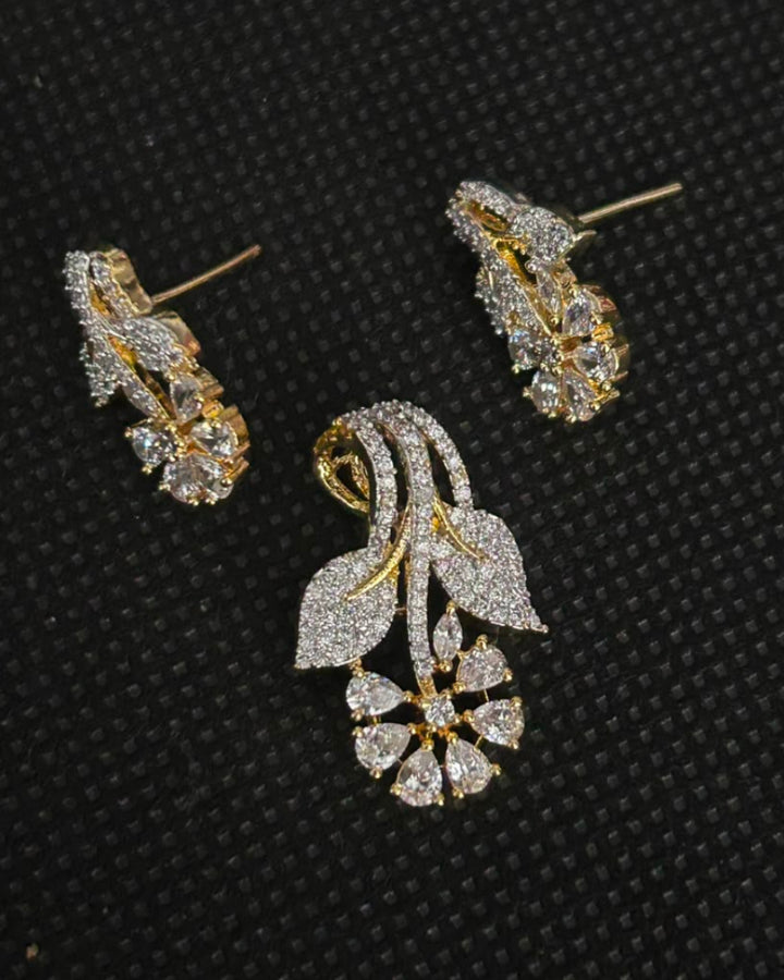 A pair of gold and diamond floral stud earrings displayed on a textured black background.