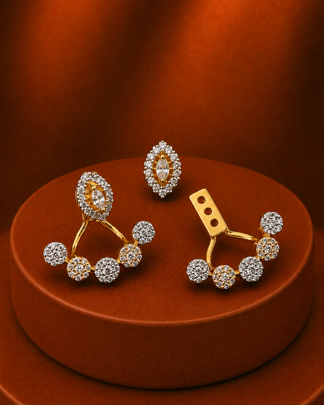 A pair of gold and crystal stud earrings displayed on a round brown pedestal against a warm brown background. The earrings feature gold-toned metal settings with multiple clear crystals, including oval and round stone clusters.