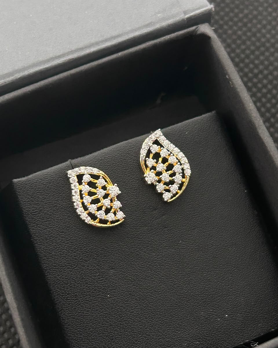 A pair of gold and crystal stud earrings displayed on a black velvet jewelry stand inside a black presentation box.