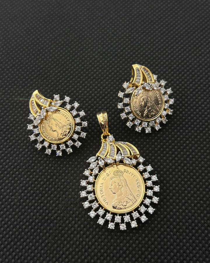A pair of gold coin earrings and a matching pendant featuring gold coins surrounded by clear cubic zirconia stones, displayed on a textured black background.