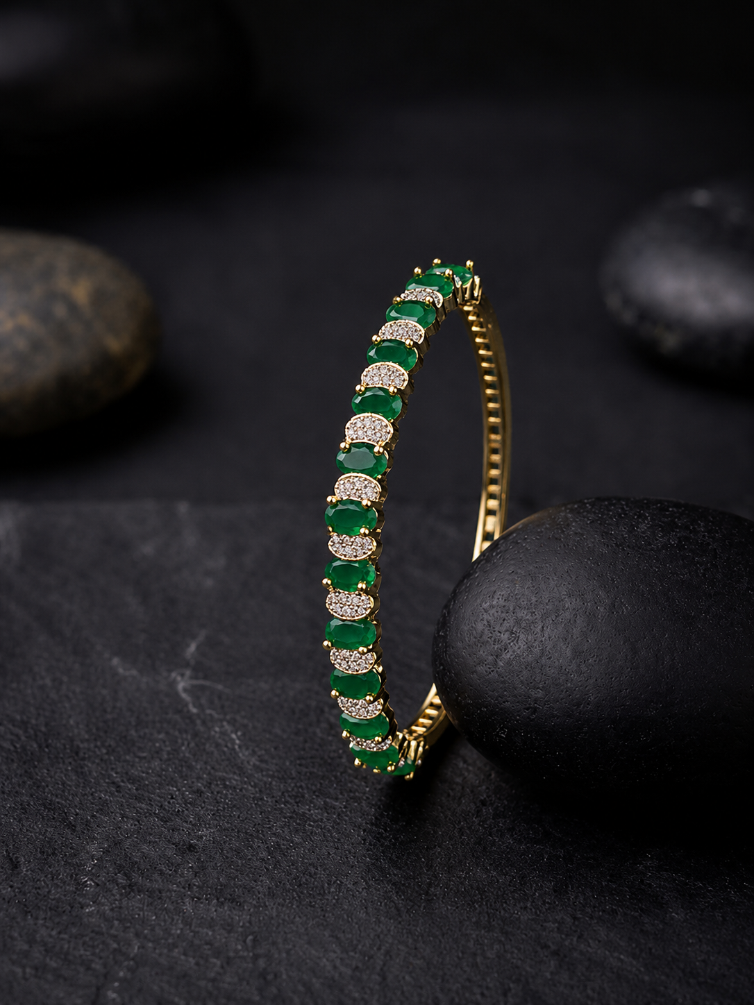 A premium gold-plated bangle available in emerald green and ruby red variants,