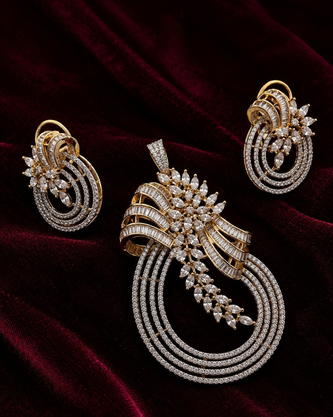 An ornate gold jewelry set featuring a large pendant, matching earrings, and a slim bracelet, all adorned with sparkling clear stones and set against a dark red velvet background.