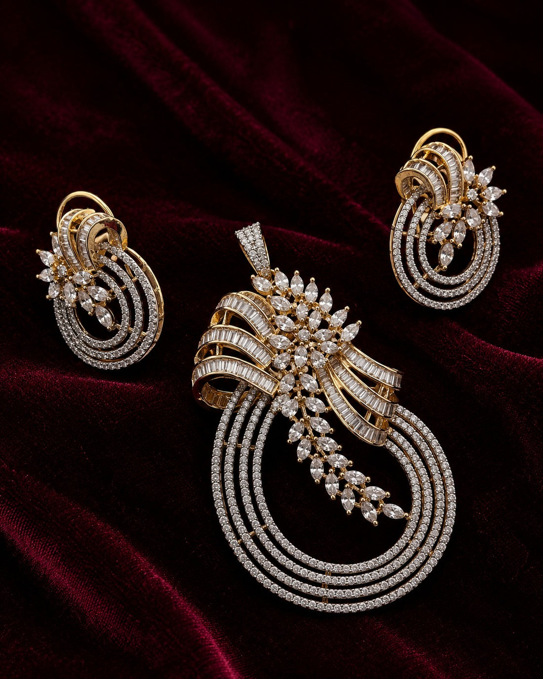 An ornate gold jewelry set featuring a large pendant, matching earrings, and a slim bracelet, all adorned with sparkling clear stones and set against a dark red velvet background.