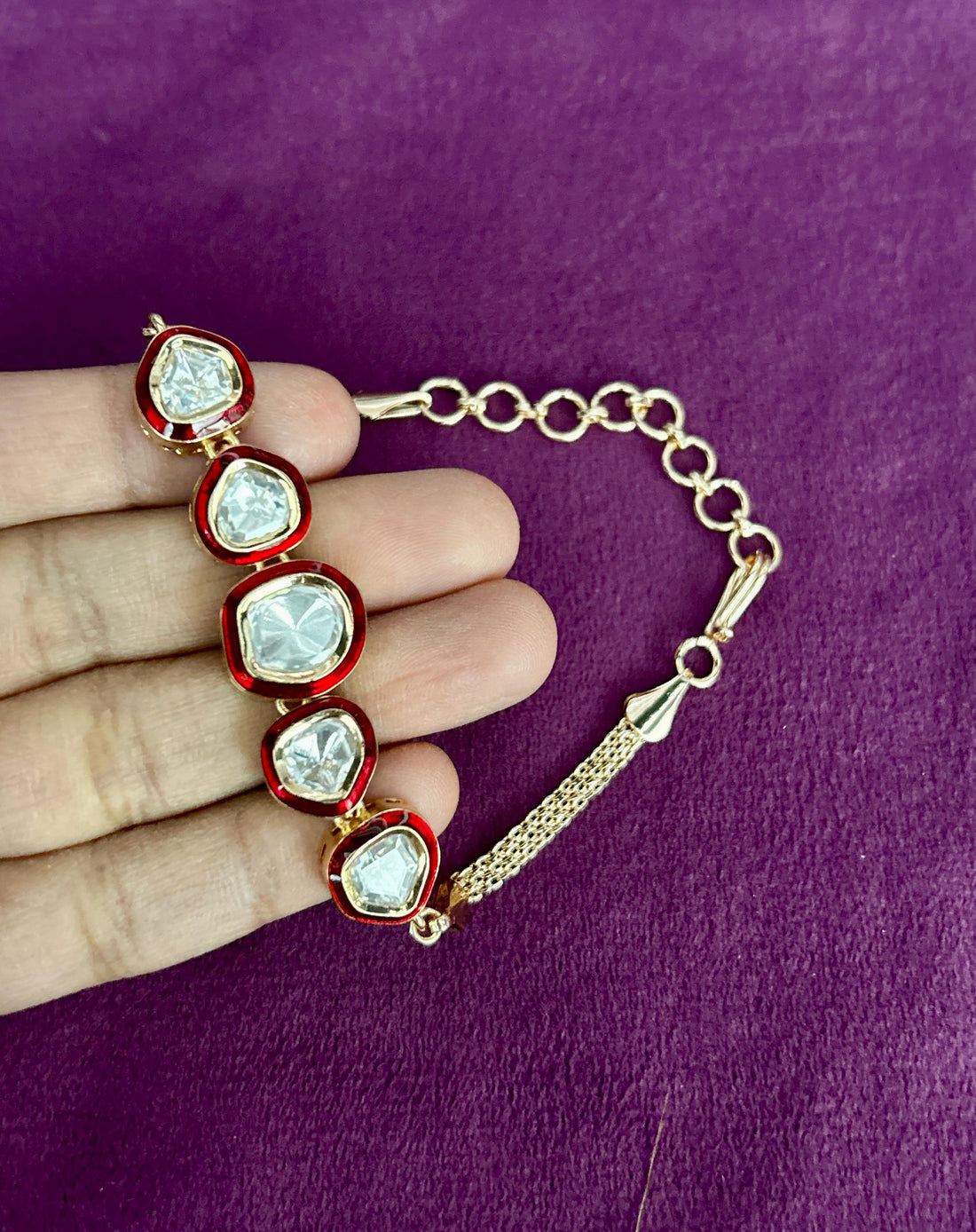Bracelet with heart-shaped gemstones held by a hand on a purple background