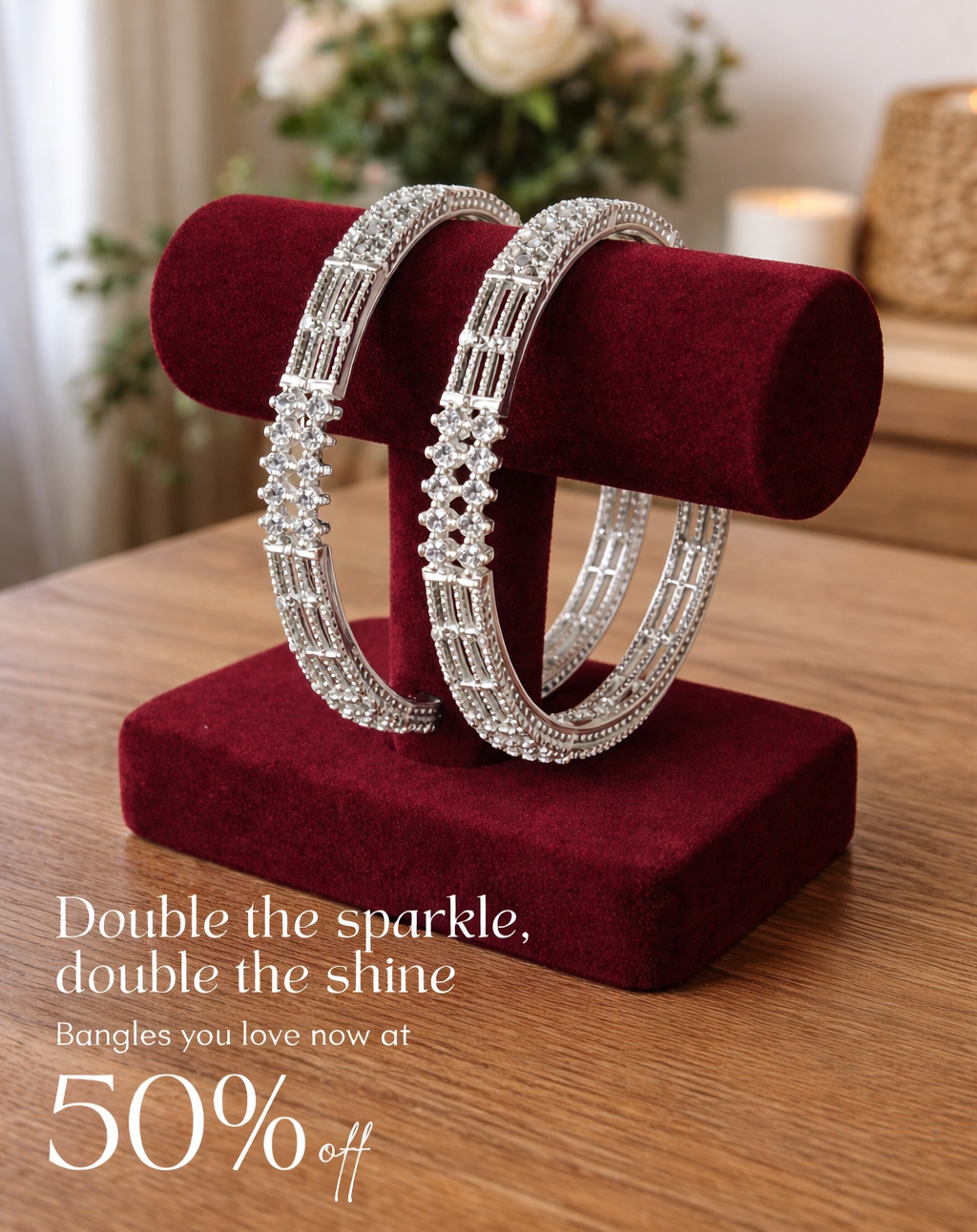 Two silver bangles on a red velvet stand with a promotional message about a discount.