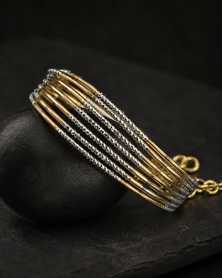 Gold and silver bracelet on a dark stone surface