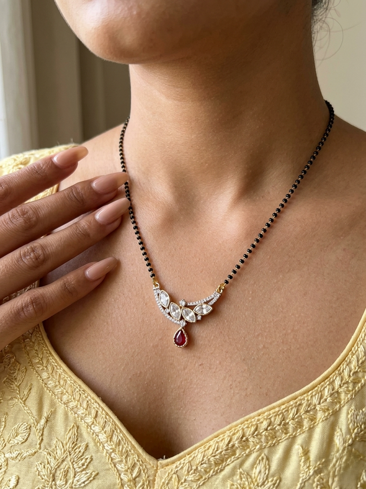 Close-up of a person wearing a diamond and ruby necklace with a gold top.
