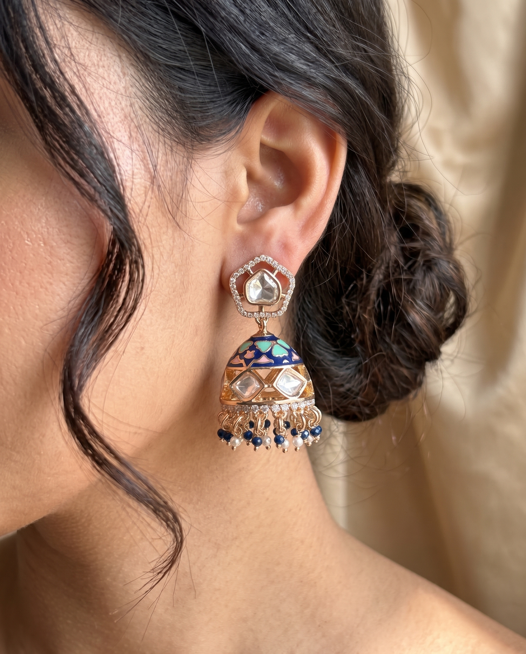 Close-up of a person wearing an ornate earring with a neutral background