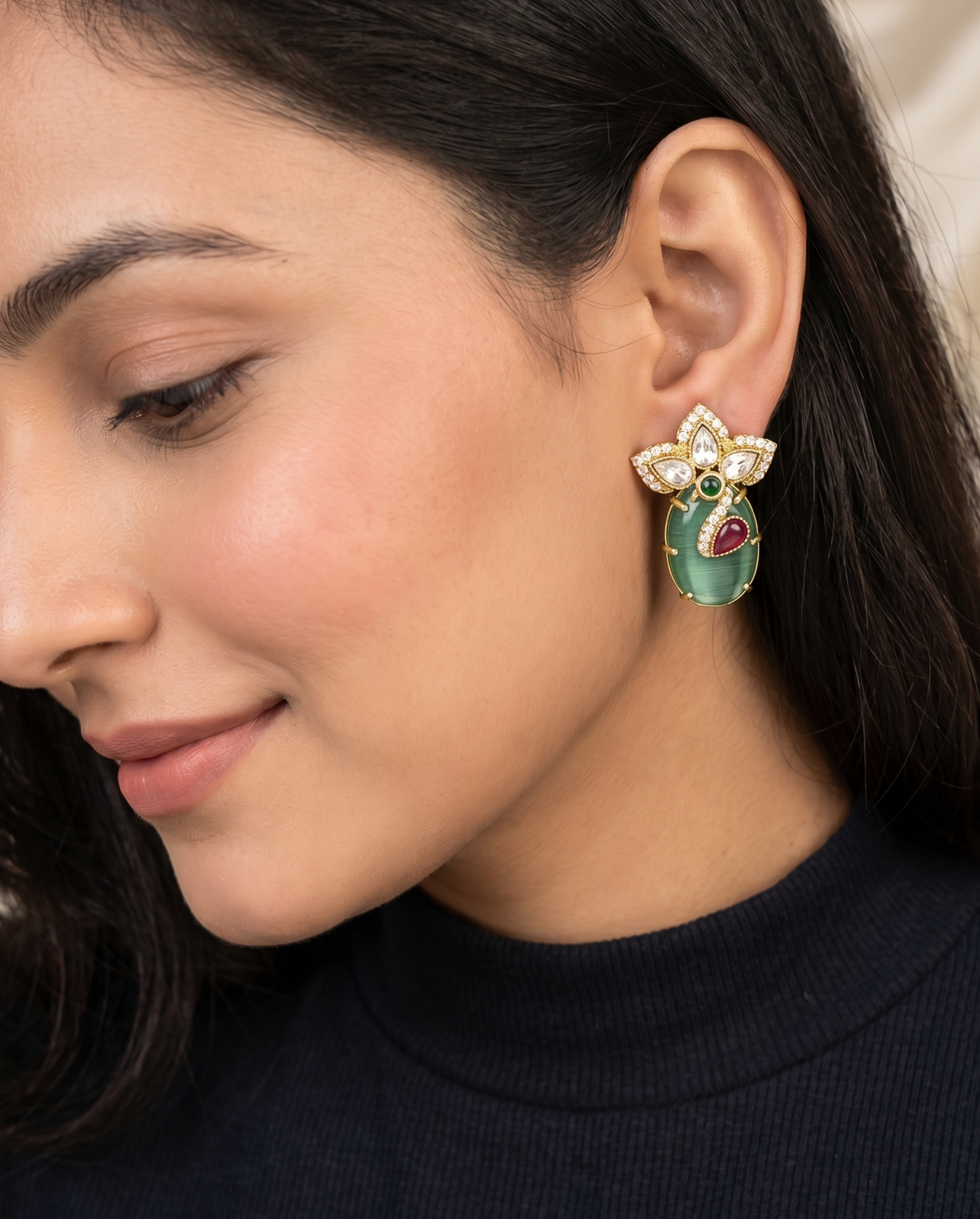 Close-up of a woman wearing a decorative earring with a green gemstone.